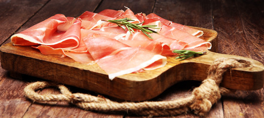 Italian prosciutto crudo or jamon with rosemary. Raw ham.