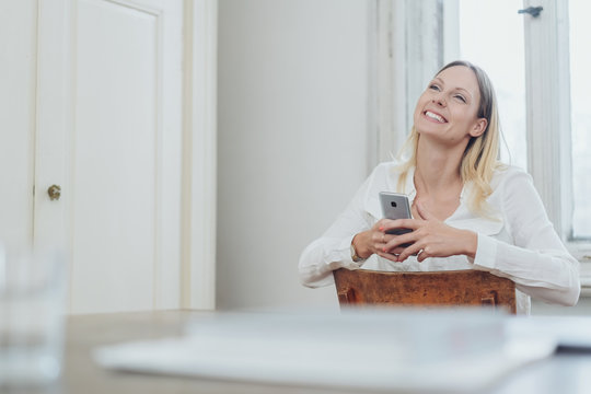 Happy young woman sitting holding a mobile