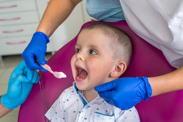 Little boy in dentistry showing his teeth to doctor