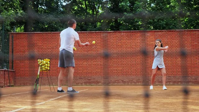 Coacher teaching young girl to playing tennis.