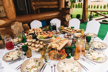 Festive rich round table with white tablecloth and chairs, served with a variety of delicious dishes, original snacks and drinks. Buffet in nature