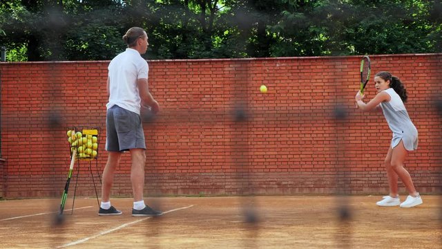 Coacher teaching young girl to playing tennis.