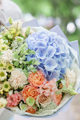 Beautiful summer bouquet. Arrangement with mix flowers. Young girl holding a flower arrangement with hydrangea. The concept of a flower shop. Content for the catalog