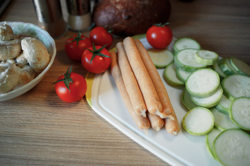tomato, mushrooms, fresh zucchini, raw sausage lie on the table