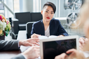 Asian young businesswoman listening to her colleagues at a meeting