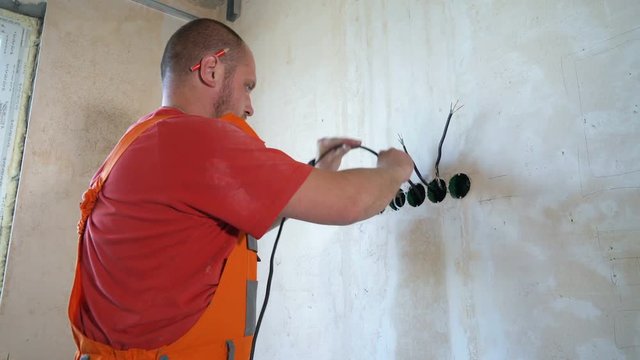 Electrician laying wiring cable lines inside of wall. Construction worker mounting electricity wires. Safety policy, technology, repair, interior design concept