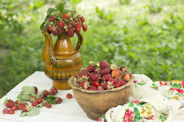 Old ceramic pot full of fresh red strawberries and clay on canvas.  Healhty food fruits diet.