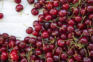 Fresh ripe cherries on a white wooden surface, top view. Flat-lay, overhead.