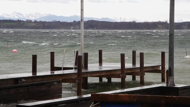 Waves are crashing into a pier during a heavy storm at lake Starnberg, Bavaria, Germany