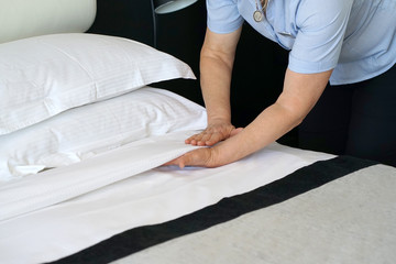 Obraz na płótnie Canvas Maid making bed in hotel room.