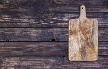 Fototapeta premium Old cutting board on dark wooden table. Top view. Copy space