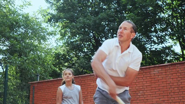 Coacher showing to the girl how to serve the ball