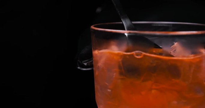 Orange alcohol cocktail in a glass, black background, strawberry, lime, black background, cold drink, ice, fresh.
