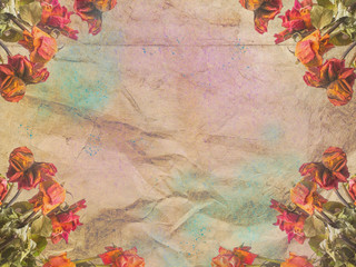 Framing of roses on a background of crumpled brown paper with blue and pink spray.