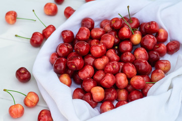 Fresh cherry on on a white blanket on a wooden bench background. fresh ripe cherries. sweet cherries