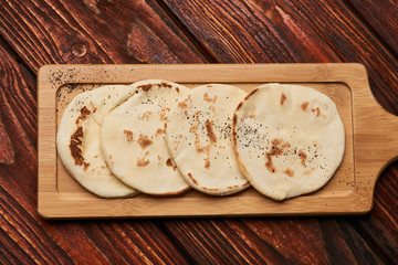 Pita bread on wooden cutting board. Corn tortilla bread on rustic wooden table