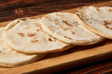 Pita bread on wooden cutting board. Corn tortilla bread on rustic wooden table