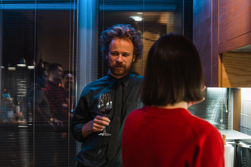 Man standing with a glass of wine and have conversation with girlfriend