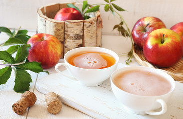 Two cups of Apple Cider and red apples in wooden  basket