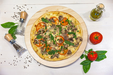 appetizing vegetarian pizza with olive oil, spices and basil leaves on a white table, flat lay