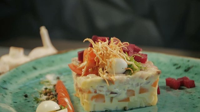 Russian traditional cuisine. Shub salad with herring. Dolly shot. On a black wooden background. Copy space.
