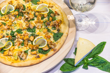 appetizing pizza with shrimps, lemon and a glass of wine on a white table, flat lay