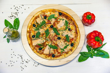 appetizing pizza with salmon, olives and rucola on a white table, flat lay