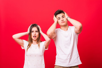 Carefree screaming couple posing and looking at the camera over red background