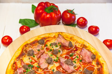 appetizing pizza with bacon, bell pepper and basil on a white table
