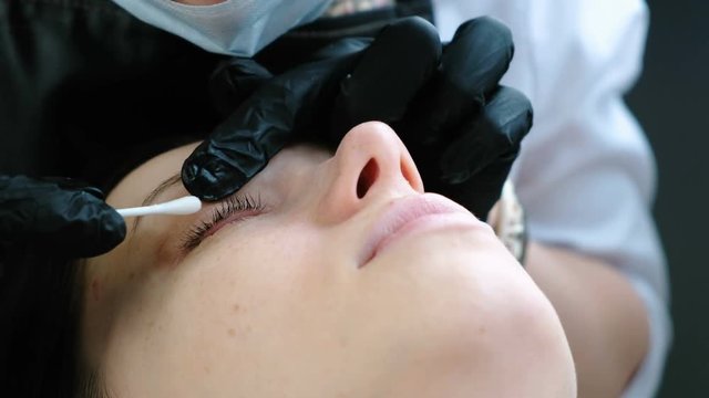 Cosmetologist rubs the client's eyelids with a cotton swab. lash lamination. Closeup eye.