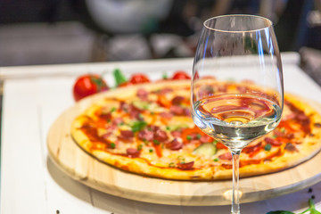 a glass of white wine on a background of delicious pizza