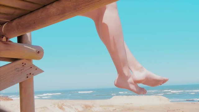 Vacation concept, swinging bare feet of woman sitting and relaxing on seach