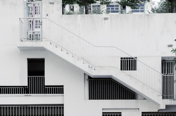 Fototapeta premium Exterior architectural background - grille windows of different shapes and sizes at white concrete wall, an external staircase on building, covered parking. Malaysia, Cyberjaya.