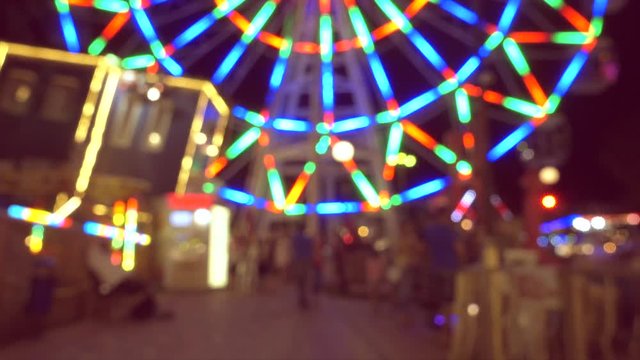 Beautiful amusement park at night, ferris wheel and carousel defocused.