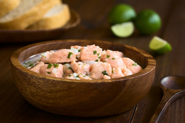 Chilean salmon ceviche prepared with onion, garlic, fresh coriander, salt and lemon juice, photographed with natural light (Selective Focus, Focus on the salmon pieces on the top of the ceviche)