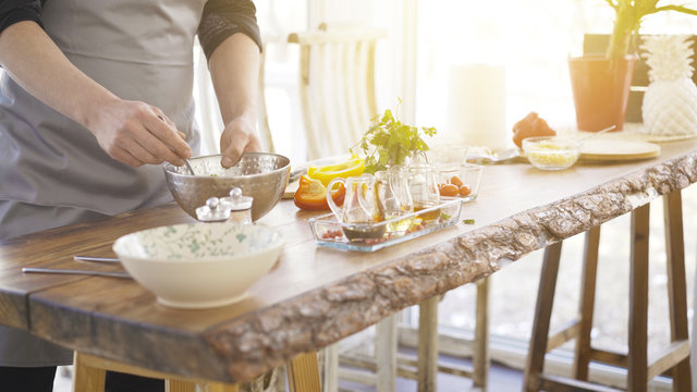 Male Chief Cooker's Hands Mixing A Salad With A Spoon In A Metal Bowl On A Kitchen Table