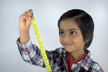 Kid with measuring tape. Smiling kid looking at numbers on tape measure. Concept of measuring height or growing tall