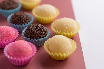 Brigadeiro, Beijinho and Bicho de Pe: sweets from Brazil. Child birthday party. Candy balls in a straight line. Colorful background.