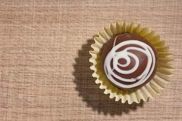 Homemade chocolate truffle.  Flat lay design of candy ball over wood.