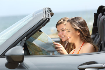 Two tourists reading a map in a convertible car