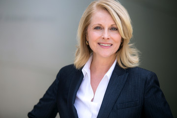Smiling head shot of a mature older female business leader, warm, friendly, likable, executive professional