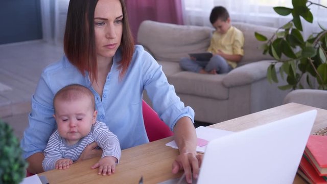 Mother working on laptop with children