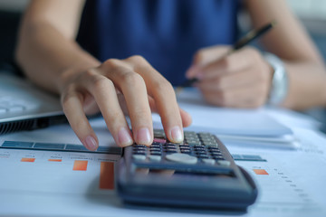 Businesswoman using calculator for analysis maketing plan, Manager calculate financial report and graph chart.  Business, Finance and Accounting concepts