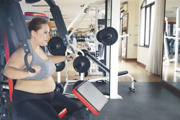 Fototapeta na wymiar Fat woman exercising with press machine