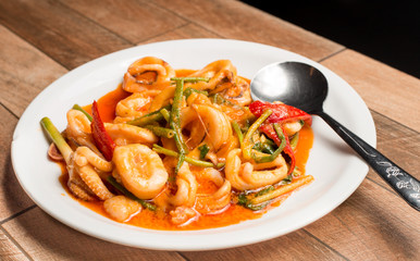 Stir-fried Squid curry powder on white dish on wood table.