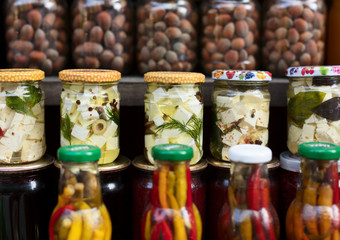 Various canned vegetables, nuts, and mushrooms in the glass jars.