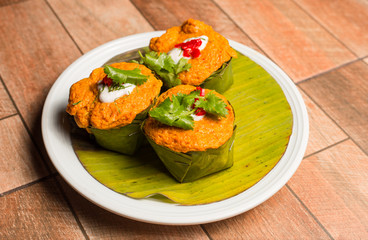 Steamed fish with curry paste on white dish on wood table.
