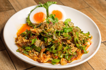 Wing Bean Shrimp Salad with boiled egg on white dish on wood table.