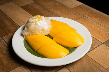 Mango and sticky rice in the white dish on wooden floor,Thai dessert popular in the summer of Thailand