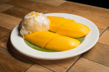 Mango and sticky rice in the white dish on wooden floor,Thai dessert popular in the summer of Thailand